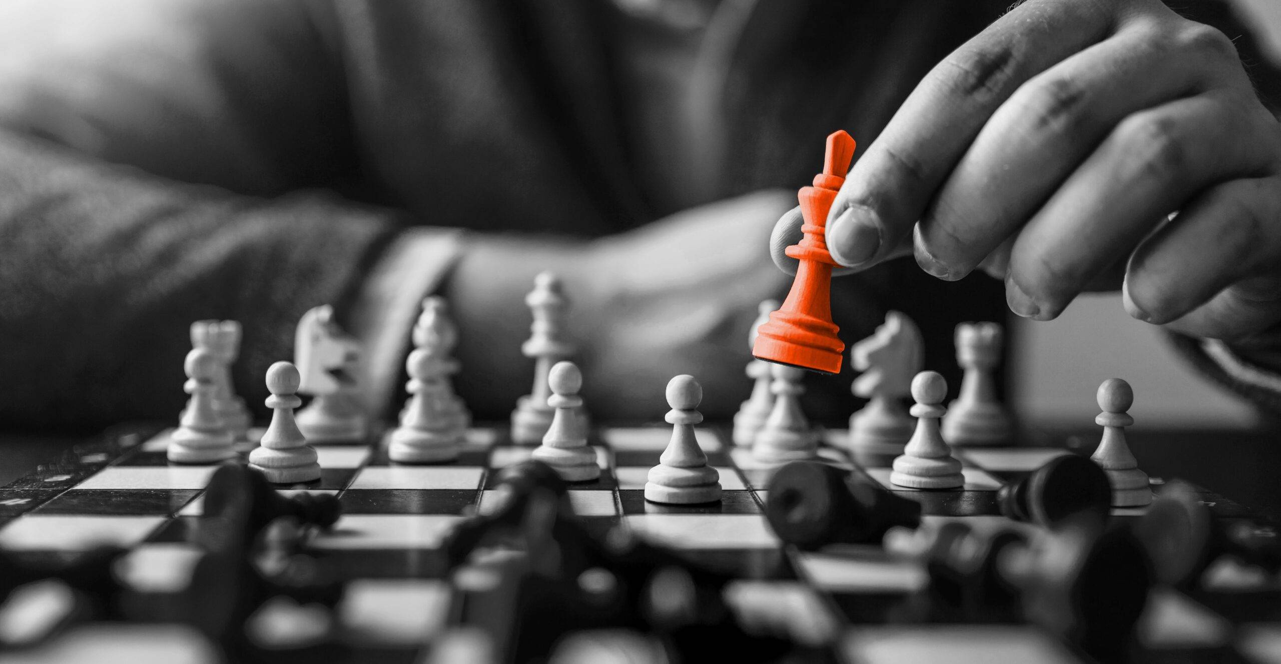 A chessboard in black and white with one player holding an orange king